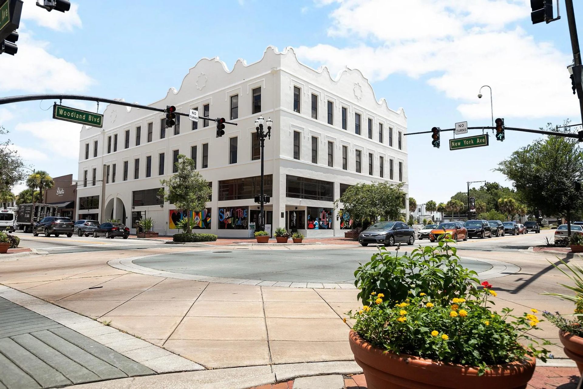 New York Plaza, a historic white Mediterranean Revival building at the corner of Woodland Boulevard and New York Avenue in downtown DeLand, Florida